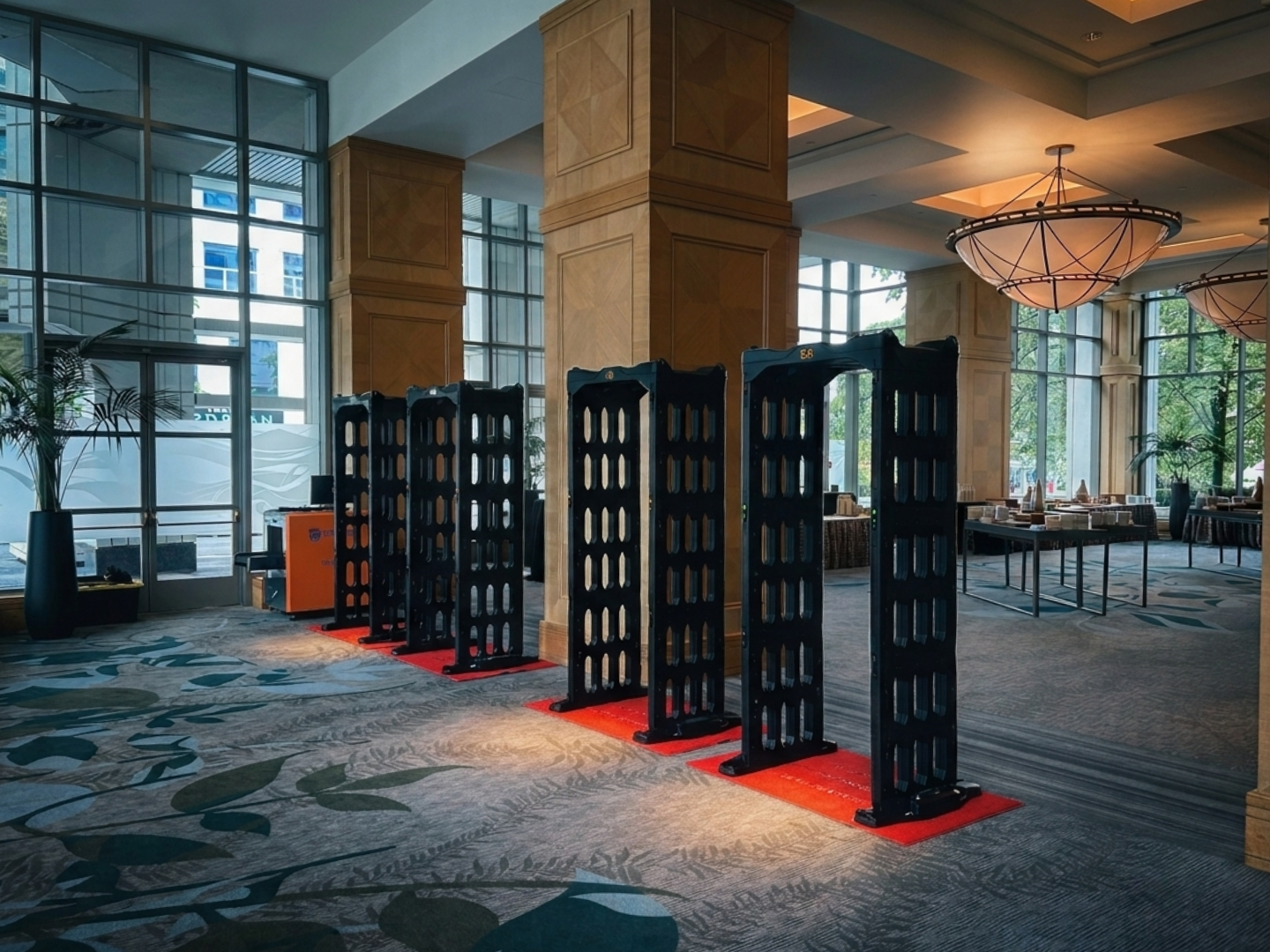 Four walk-through metal detectors set up on red mats inside a hotel lobby
