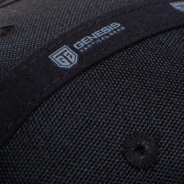 Black cotton inside weave of the baseball cap. A black ribbon is stitched across the inside of the baseball from the bottom left of the picture to the right top angle and displaying a white Genesis Tactical Gear logo and name on. An eyelet is stitched with black thread in the fabric, on either side of the branded ribbon.