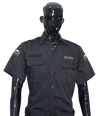 Picture of the front of a black tactical shirt with an unbuttoned collar, two front pockets, and buttoned shoulder straps, worn by a shiny black dummy cut at the wrists and the hips at the bottom of the image. Two embroidered black shoulder patches and one embroidered left chest patch display the GENESIS brand in white, topped by the fluorescent moon crescent on the shoulders. The right chest has a Velcro patch.